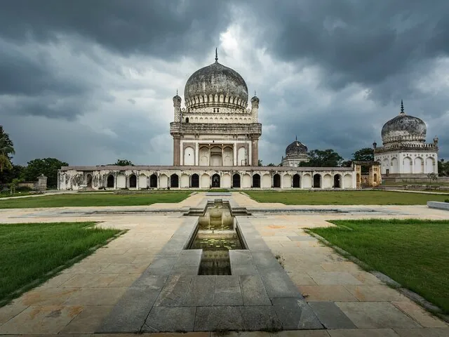 Qutb Shahi Tombs with a reflecting pool and dramatic cloudy sky