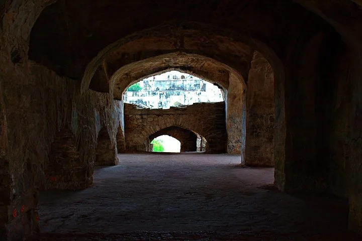 Blick durch einen dunklen, gewölbten Steinkorridor in der Festung Golkonda
