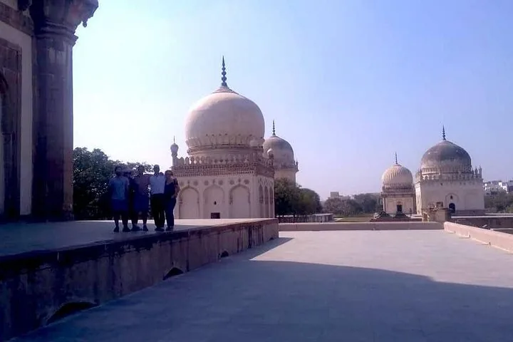 Eine Gruppe von Menschen auf einer Terrasse mit Blick auf die Qutb-Shahi-Gräber